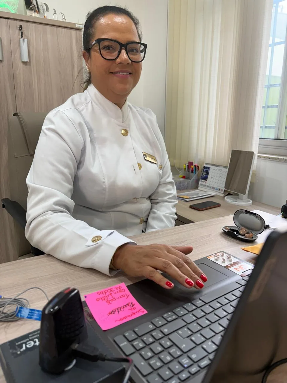 Carla Gonçalves em seu consultório com aparelhos auditivos utilizados no processo de Reabilitação Auditiva